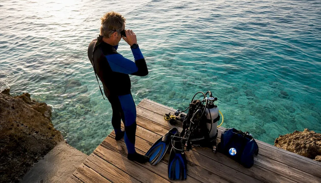 Man staat op het punt om vanaf de pier op Bonaire het water in te duiken